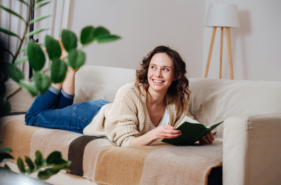A woman lying on a sofa reading a book