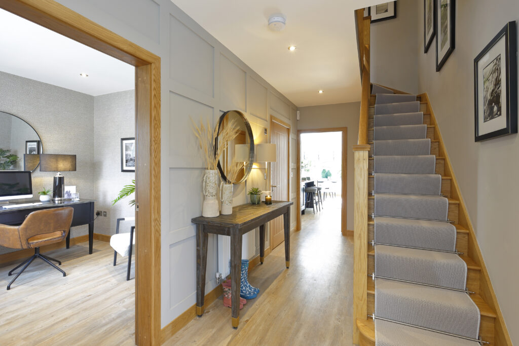 The hallway and staircase of a show home, looking through to the kitchen