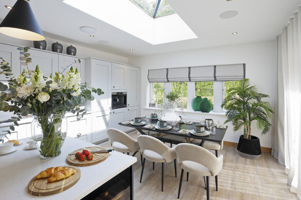 An open-plan show home kitchen and dining area lit by a lantern roof light