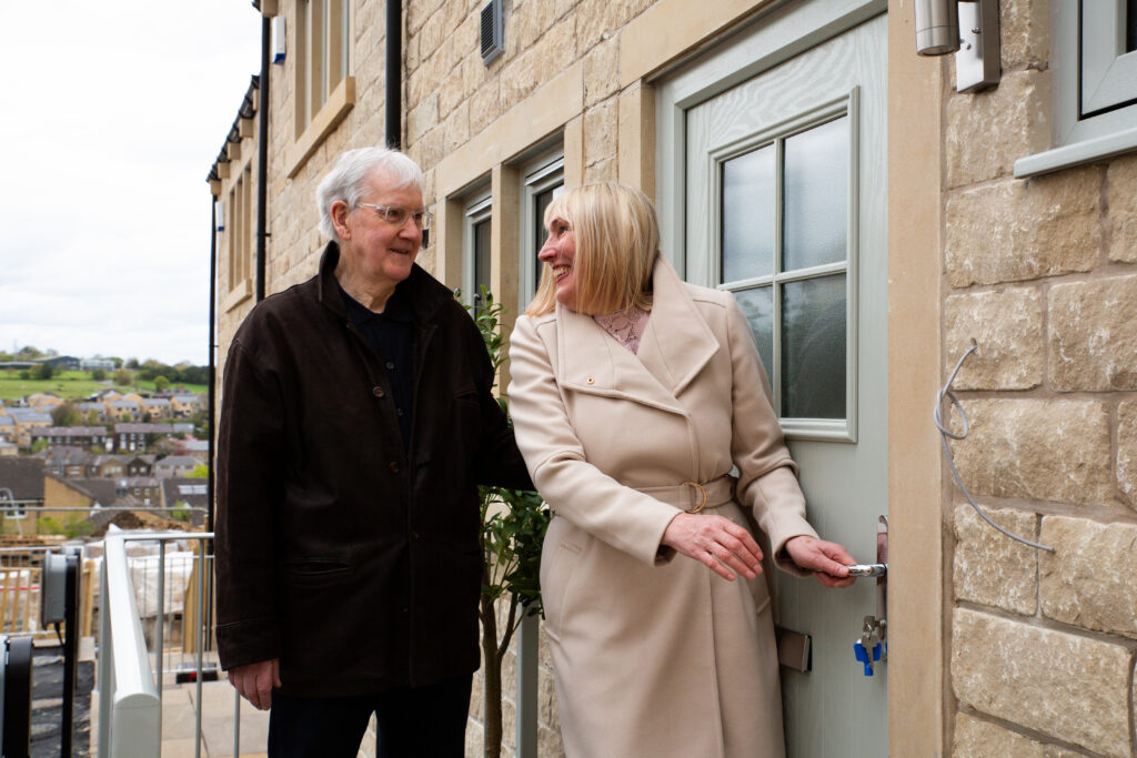 A couple at the front door of their new home, with the keys still in the lock
