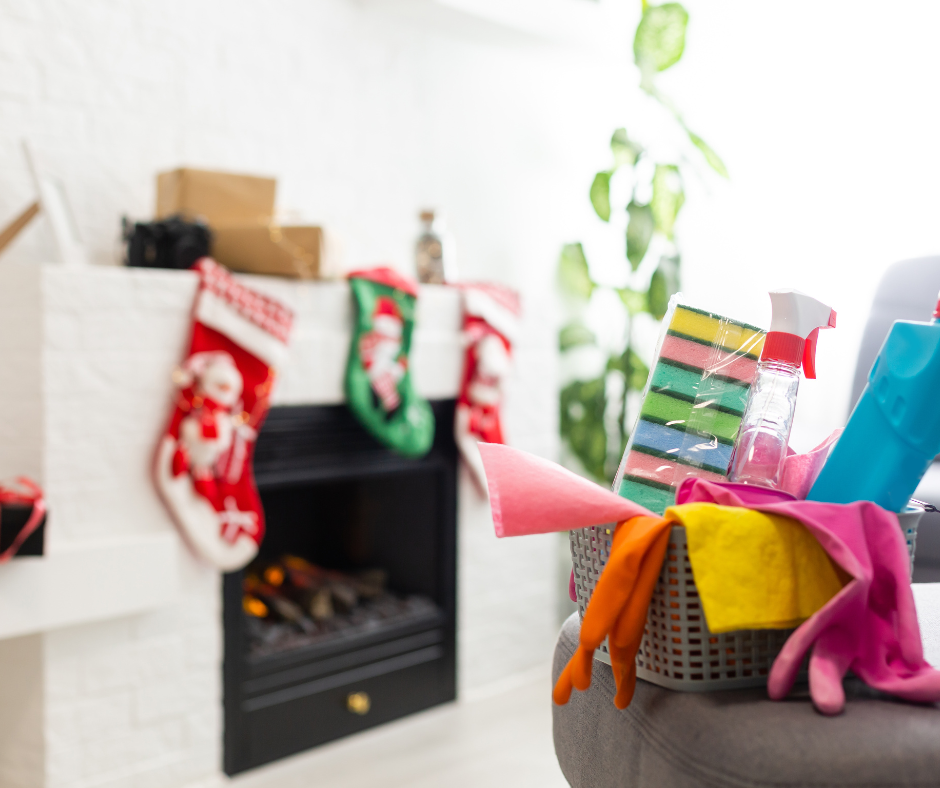 A basket of cleaning supplies beside a fireplace hung with Christmas stockings