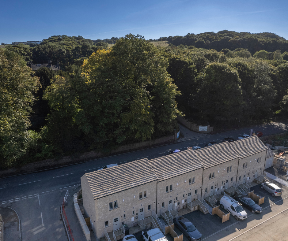 Aerial view of a row of new stone terraced homes beside woodland