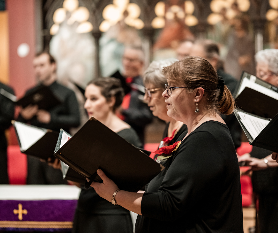 Members of a choir singing from folders inside a church