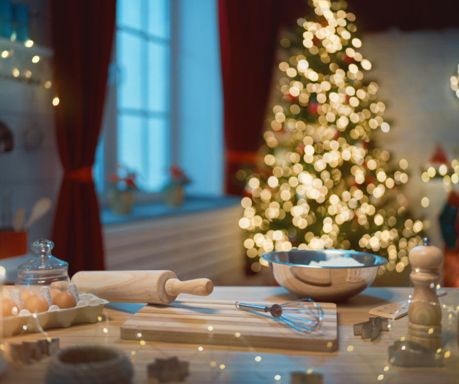 Baking equipment on a kitchen table with a lit Christmas tree behind