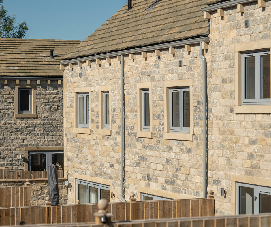 The rear elevation of new stone homes with garden fences