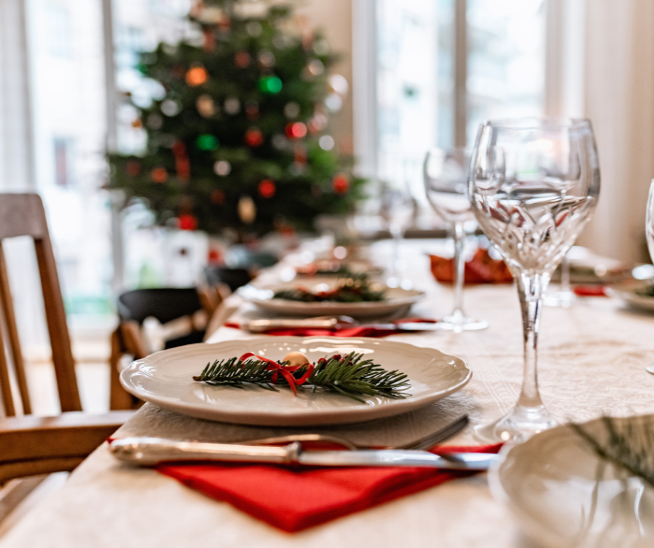 A dining table set for Christmas dinner with a Christmas tree behind