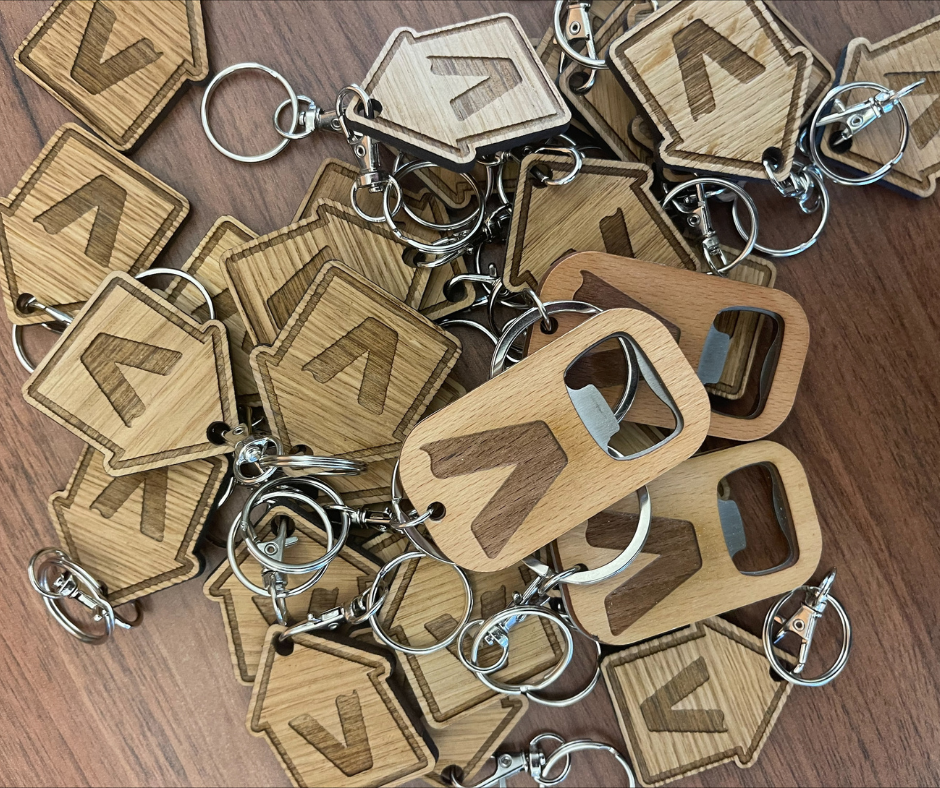 A pile of wooden Vivly Living keyrings and bottle openers