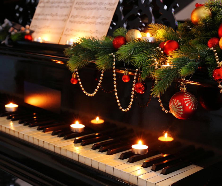 Candles and a Christmas garland on a piano with sheet music