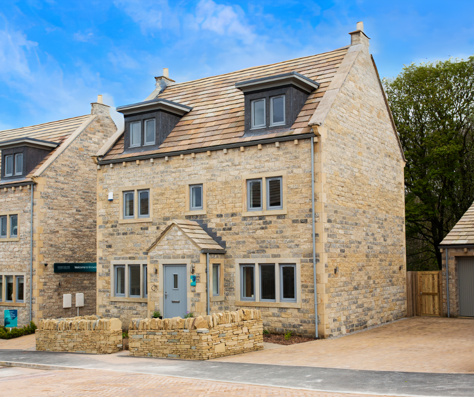 A newly built detached stone show home with a sign beside the front door