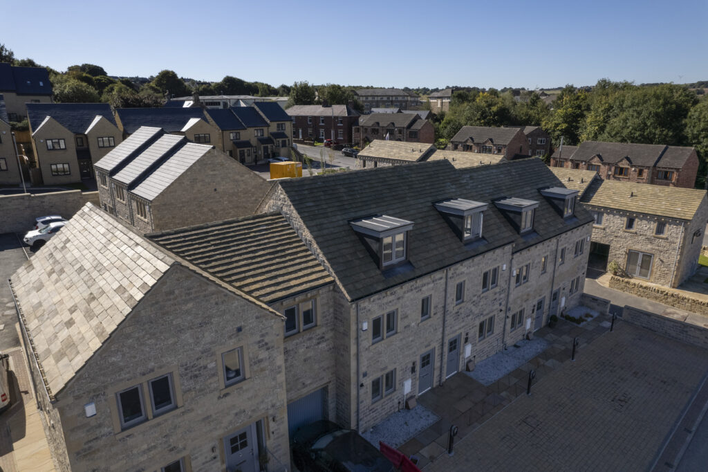 An aerial view of a terrace of new stone homes with dormer windows