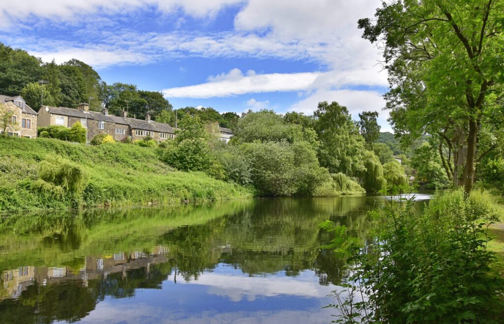 Stone cottages above a still mill pond surrounded by trees