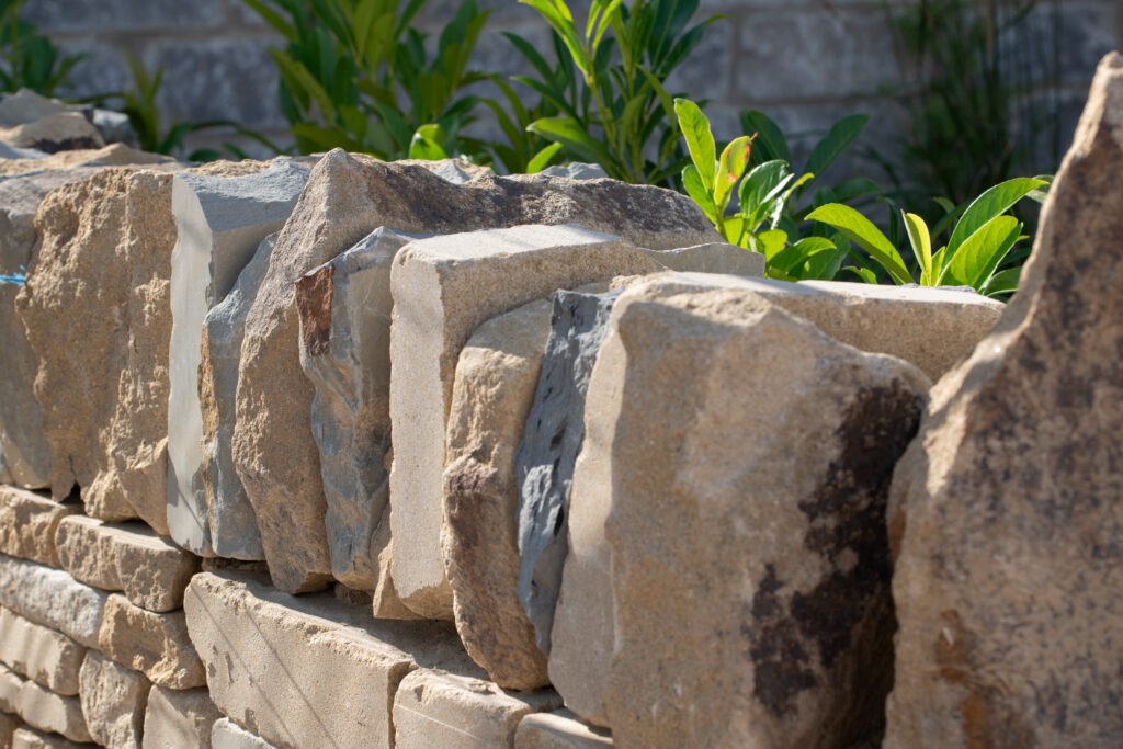 A close-up of a dry stone wall with green planting behind it