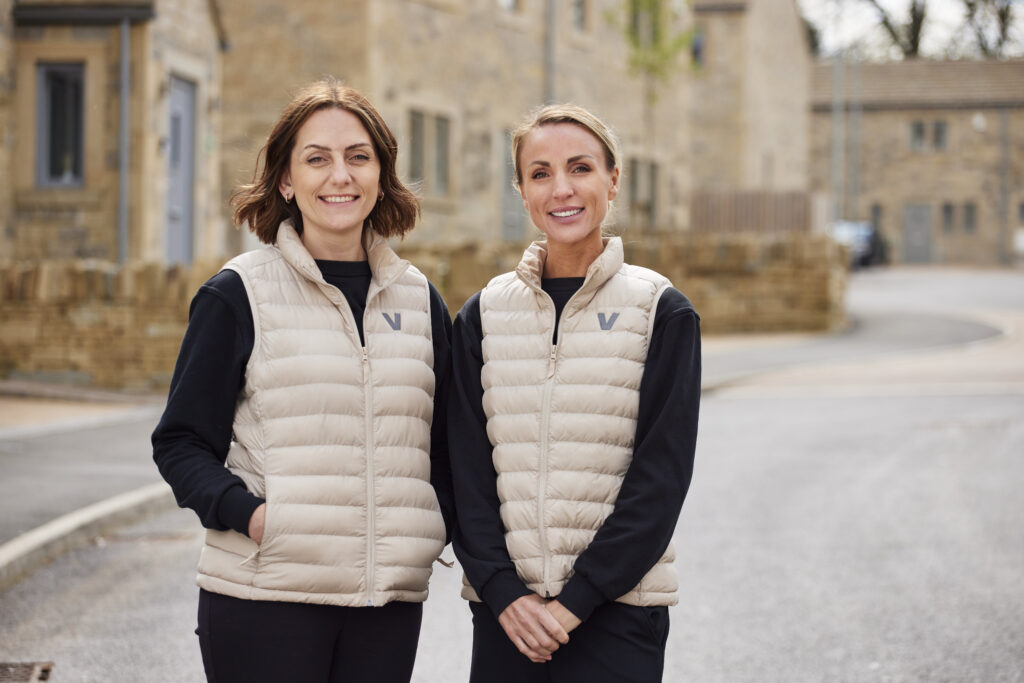 Two members of the Vivly Living sales team standing outside new stone homes